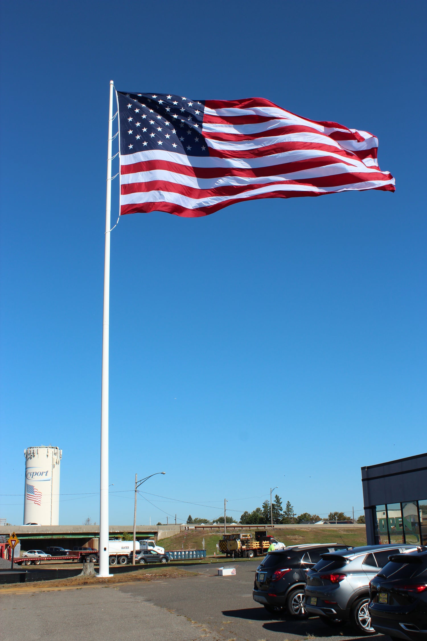 Large cone-tapered steel flagpole flying American flag at commercial property