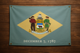 Realistic Delaware flag with brass grommets in all 4 corners mounted on a wood wall