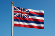 Realistic looking Hawaii flag flying on a flagpole with clear blue, sunny skies behind it