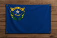 Realistic Nevada flag with a brass grommet in each corner mounted to a wood wall