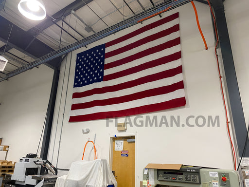 Large American flag hanging on a wall in an industrial setting for sale